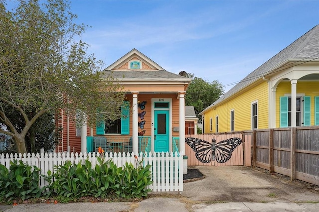 shotgun-style home with a porch and a fenced front yard