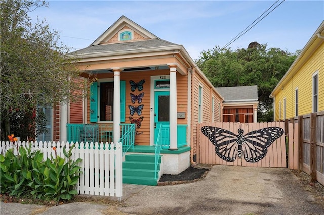 exterior space with a gate, fence private yard, a porch, and a shingled roof