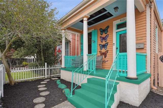 entrance to property featuring covered porch and fence