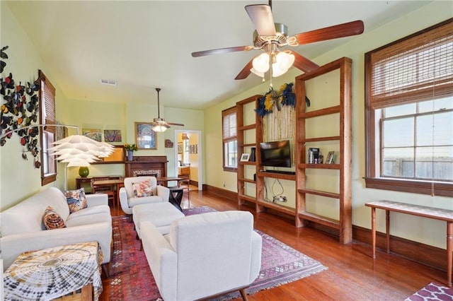 living area featuring ceiling fan, baseboards, wood finished floors, and visible vents