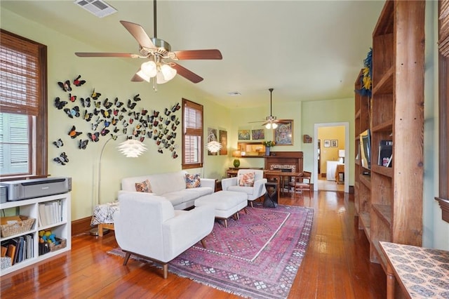 living area with wood-type flooring, a ceiling fan, visible vents, and a healthy amount of sunlight