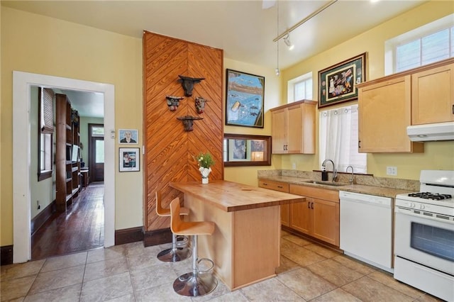 kitchen with wooden counters, under cabinet range hood, a breakfast bar, a sink, and white appliances