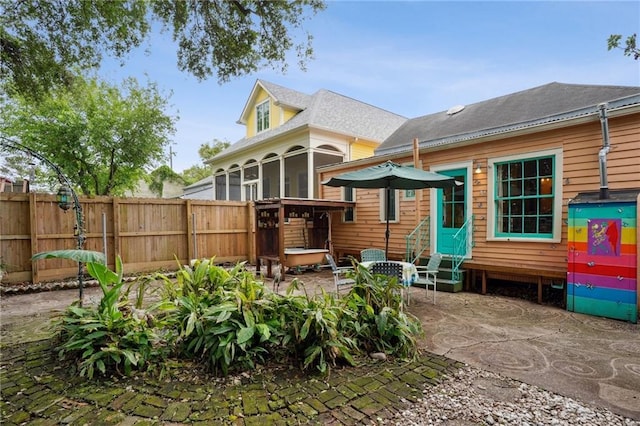 back of house with entry steps, a sunroom, a patio, and fence