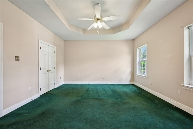 4761 Sharp Rd, Mandeville, LA 70471 - empty room featuring dark carpet, a ceiling fan, and a tray ceiling