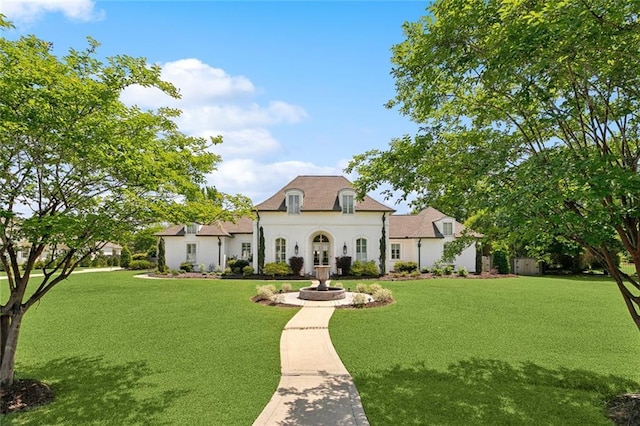 french country style house featuring stucco siding and a front lawn