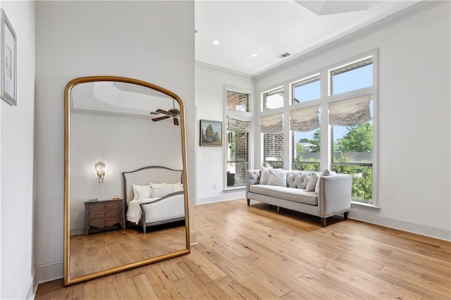 living area with ornamental molding, baseboards, a wealth of natural light, and light wood-style floors