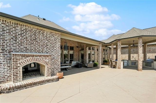 view of patio with a grill, exterior kitchen, and an outdoor brick fireplace