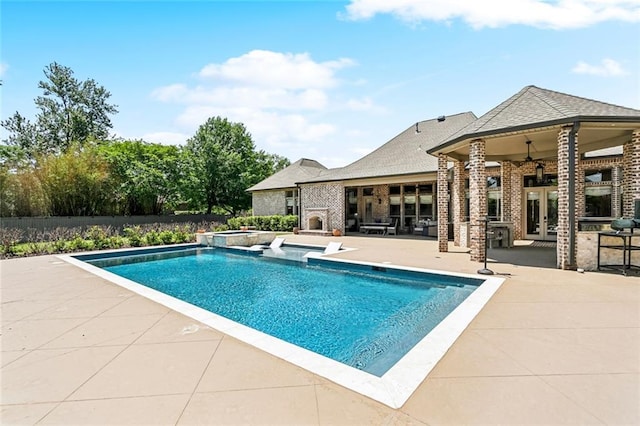 view of swimming pool featuring a pool with connected hot tub, a fireplace, a patio area, ceiling fan, and french doors