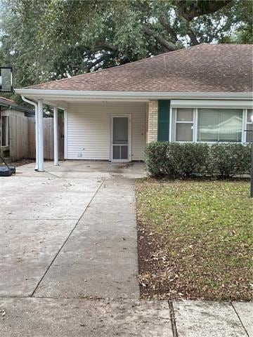 536 Olive Dr, Harvey, LA 70058 - view of front facade featuring concrete driveway, fence, a carport, and roof with shingles