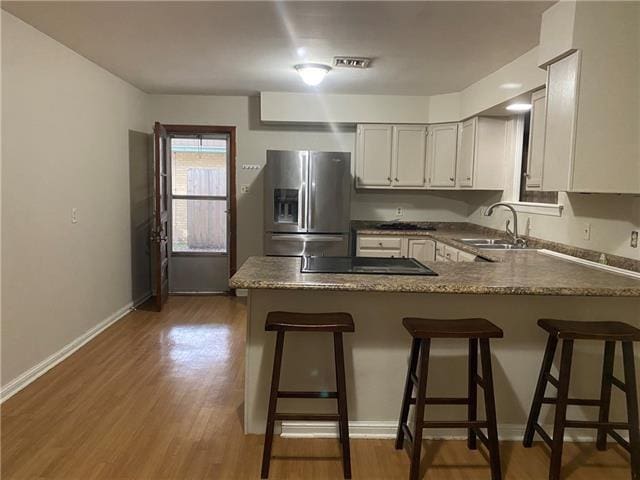 536 Olive Dr, Harvey, LA 70058 - kitchen featuring stainless steel fridge with ice dispenser, a sink, a peninsula, black electric stovetop, and light wood-style floors