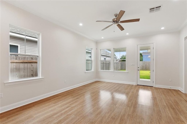 empty room featuring wood finished floors, baseboards, visible vents, a ceiling fan, and crown molding
