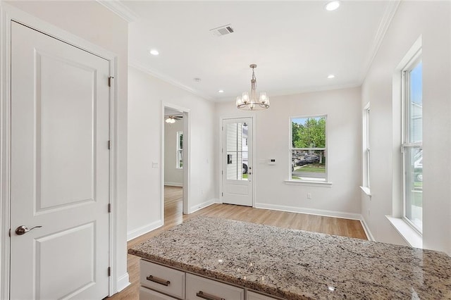 entryway with ornamental molding, light wood-style floors, visible vents, and a notable chandelier