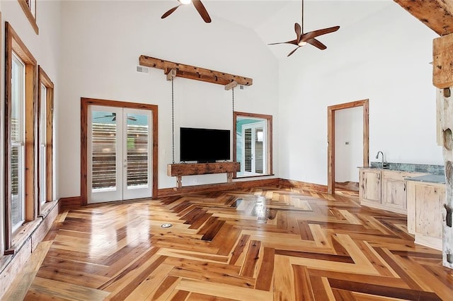 unfurnished living room with visible vents, a ceiling fan, a sink, french doors, and high vaulted ceiling