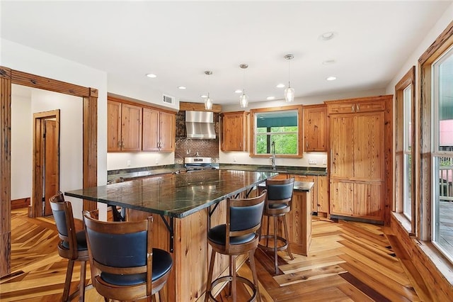 kitchen featuring wall chimney exhaust hood, a center island, visible vents, recessed lighting, and stainless steel stove