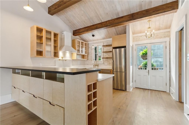 kitchen with vaulted ceiling with beams, open shelves, light wood-type flooring, wall chimney range hood, and freestanding refrigerator