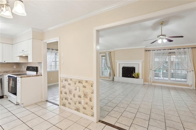 kitchen with electric range, under cabinet range hood, light tile patterned floors, white cabinetry, and a fireplace with raised hearth