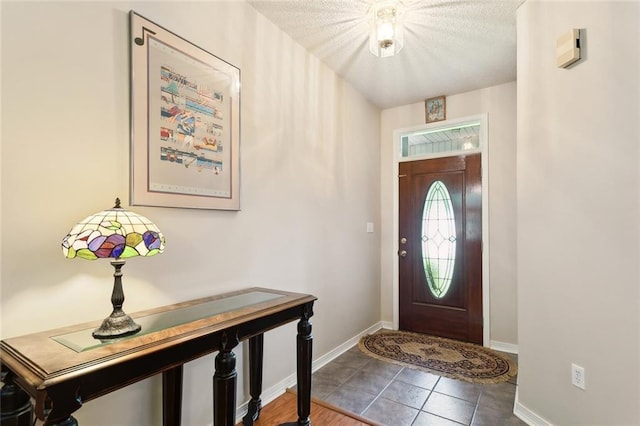 tiled entryway featuring baseboards and a textured ceiling