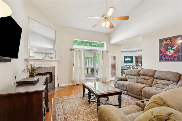 living room with high vaulted ceiling, ceiling fan, wood finished floors, and a tiled fireplace