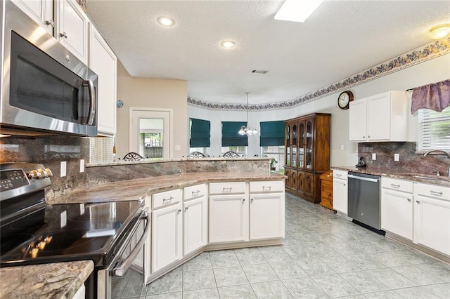 kitchen featuring stainless steel appliances, a sink, a textured ceiling, and plenty of natural light