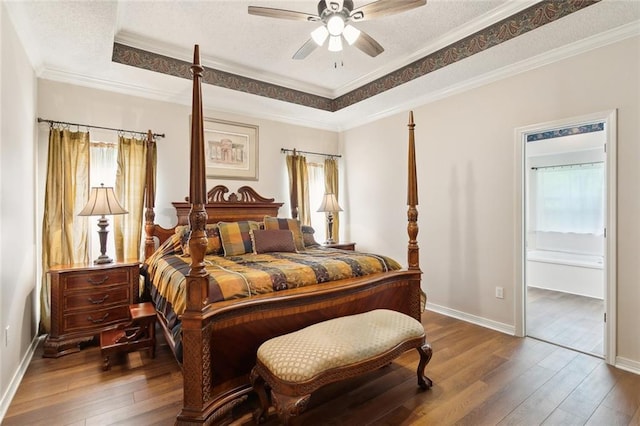 bedroom featuring hardwood / wood-style flooring, baseboards, a textured ceiling, and a raised ceiling