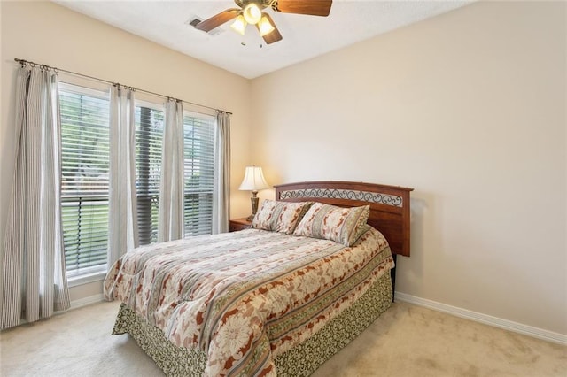 carpeted bedroom with visible vents, baseboards, and ceiling fan
