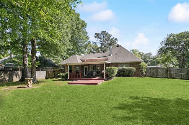rear view of property with a shingled roof, a fenced backyard, a yard, a wooden deck, and brick siding