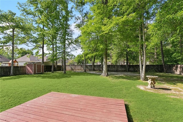 view of yard with a wooden deck, a fenced backyard, an outdoor structure, and a storage shed