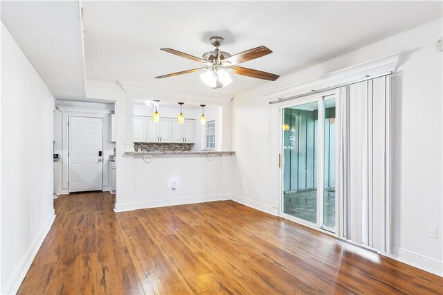 2121 Mediamolle Dr, New Orleans, LA 70114 - kitchen with ceiling fan, wood finished floors, hanging light fixtures, baseboards, and white cabinetry