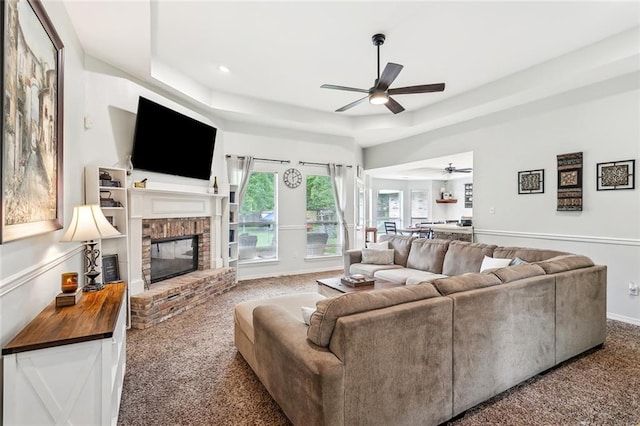 1229 Hampton Ct, Slidell, LA 70460 - living room featuring carpet flooring, a tray ceiling, baseboards, a ceiling fan, and a fireplace