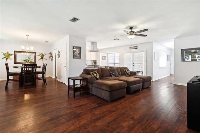living area featuring visible vents, baseboards, dark wood finished floors, and ceiling fan with notable chandelier