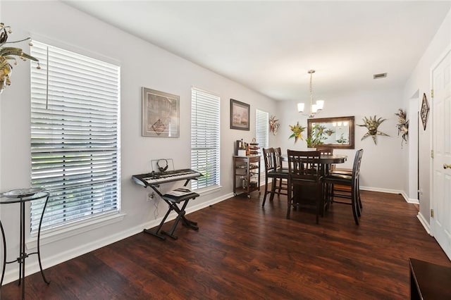 dining room featuring wood finished floors, a chandelier, visible vents, and baseboards