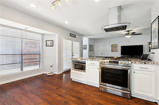 kitchen featuring appliances with stainless steel finishes, island range hood, light stone countertops, and baseboards