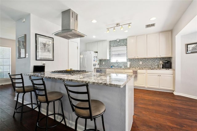 kitchen with a kitchen breakfast bar, island range hood, appliances with stainless steel finishes, and a sink