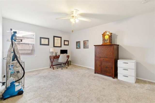 carpeted office space featuring baseboards and ceiling fan
