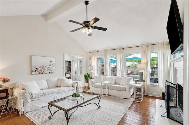 living room with beam ceiling, light wood-style floors, high vaulted ceiling, ceiling fan, and a fireplace