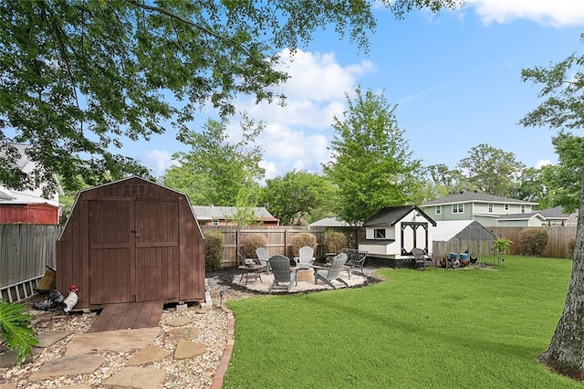 view of yard featuring a storage shed, a fenced backyard, an outdoor fire pit, and an outdoor structure