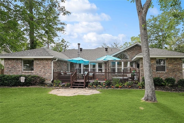 rear view of house with a wooden deck, a patio area, brick siding, a lawn, and roof with shingles