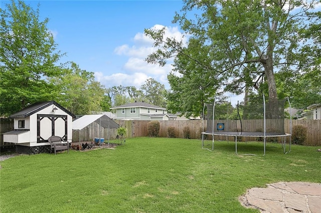 view of yard featuring a fenced backyard, an outbuilding, a storage shed, and a trampoline
