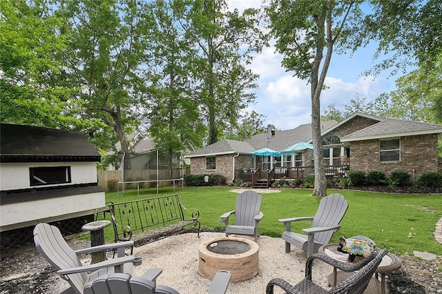 view of patio / terrace with a trampoline, a deck, and an outdoor fire pit