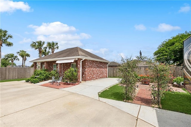 view of front of property with a patio, a fenced backyard, and brick siding
