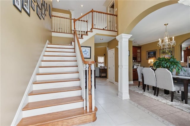 stairs featuring tile patterned floors, ornate columns, arched walkways, and an inviting chandelier
