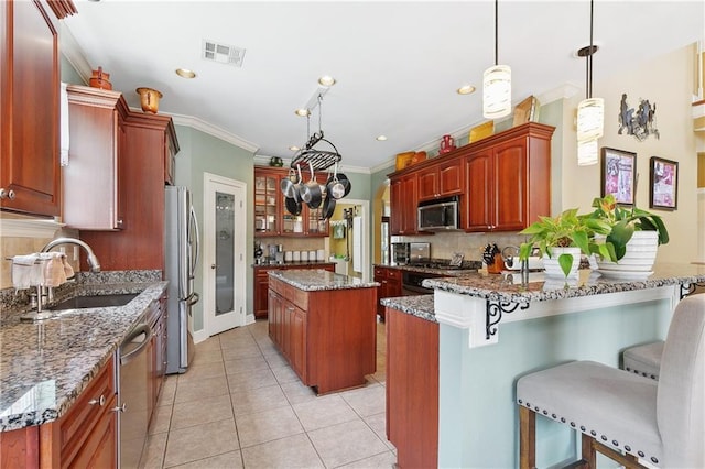kitchen featuring a sink, a kitchen breakfast bar, crown molding, visible vents, and appliances with stainless steel finishes