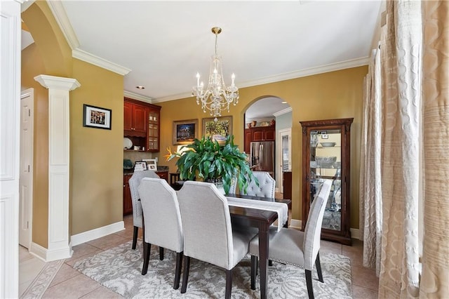 dining space featuring arched walkways, a chandelier, light tile patterned floors, ornamental molding, and baseboards