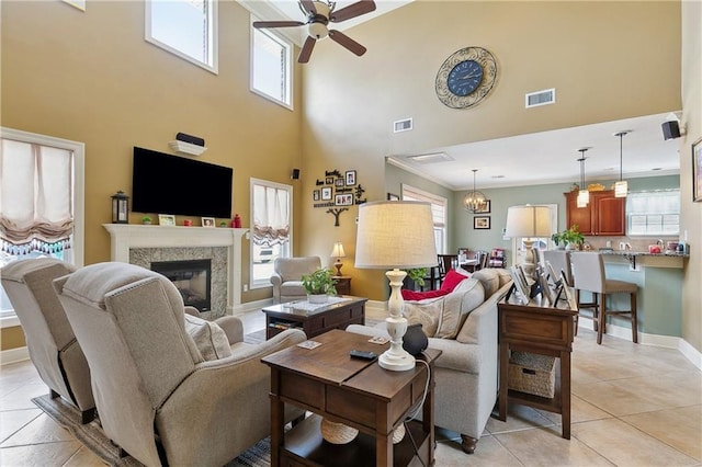 living area featuring a high ceiling, visible vents, and ceiling fan with notable chandelier