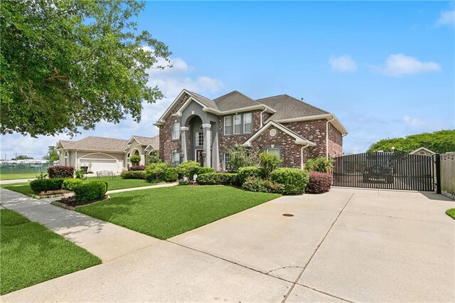 view of front of property with a gate, brick siding, fence, a front yard, and concrete driveway