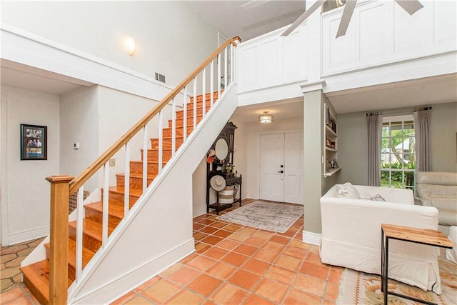 foyer entrance featuring a high ceiling, visible vents, stairway, and baseboards