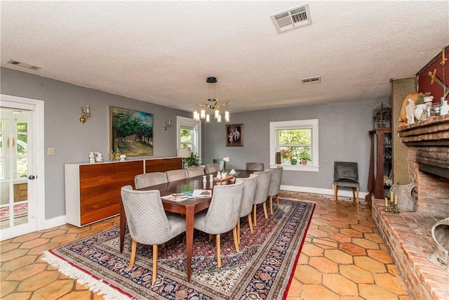 dining room featuring a chandelier, visible vents, and a textured ceiling