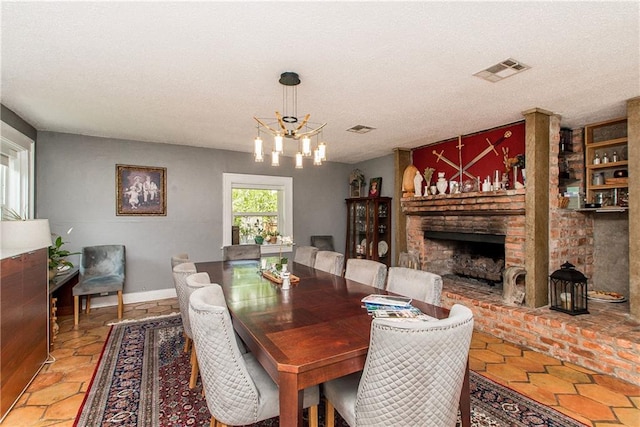 dining space with an inviting chandelier, visible vents, a textured ceiling, and a fireplace