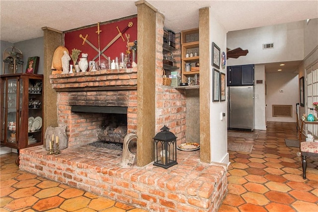 living room featuring visible vents, a textured ceiling, and a fireplace