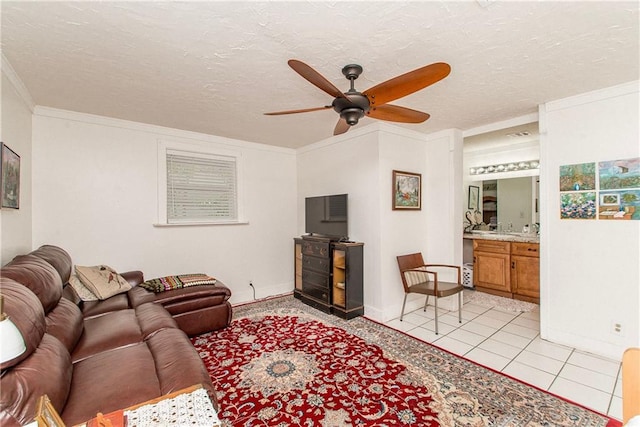 living room with light tile patterned flooring, ceiling fan, crown molding, baseboards, and a textured ceiling